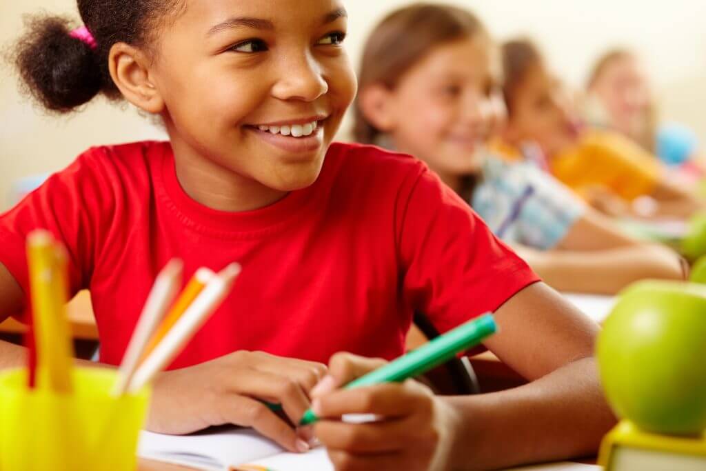 Smiling boy coloring with classmates