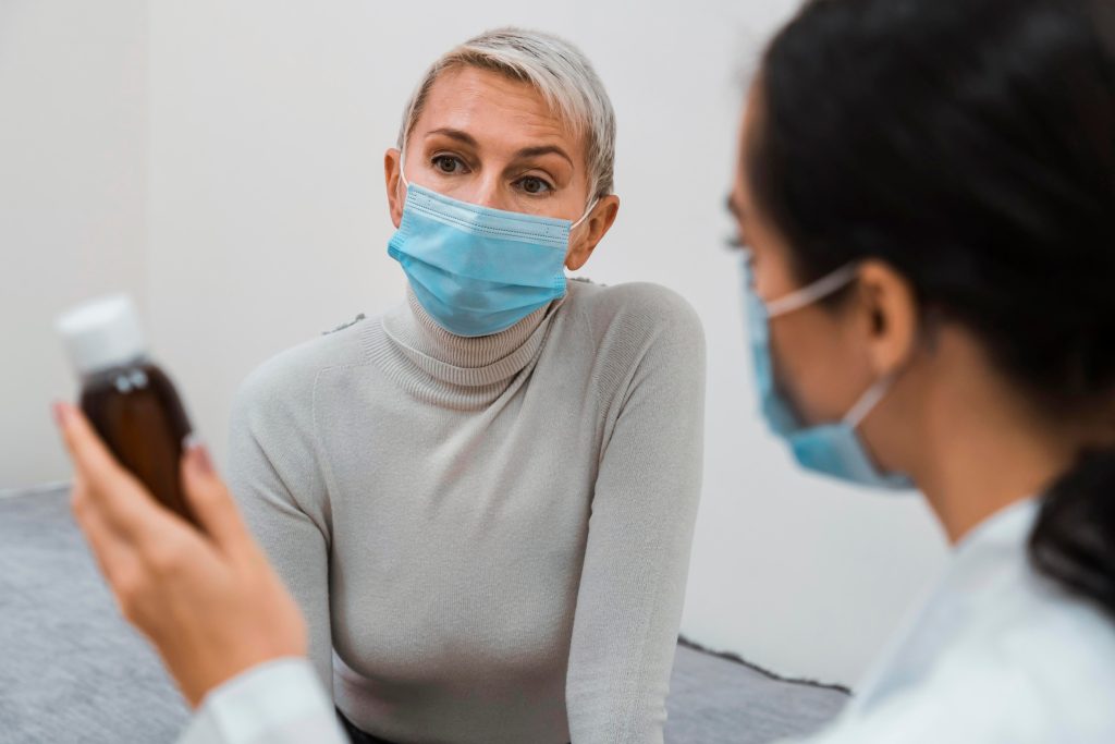 Doctor wearing a face mask discussing medication with a patient