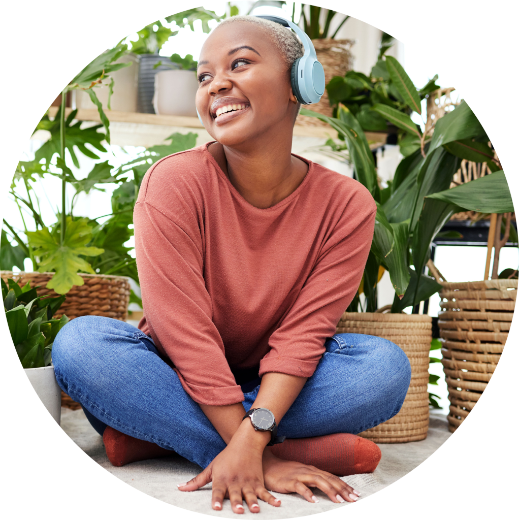 Smiling woman wearing headphones sitting among houseplants