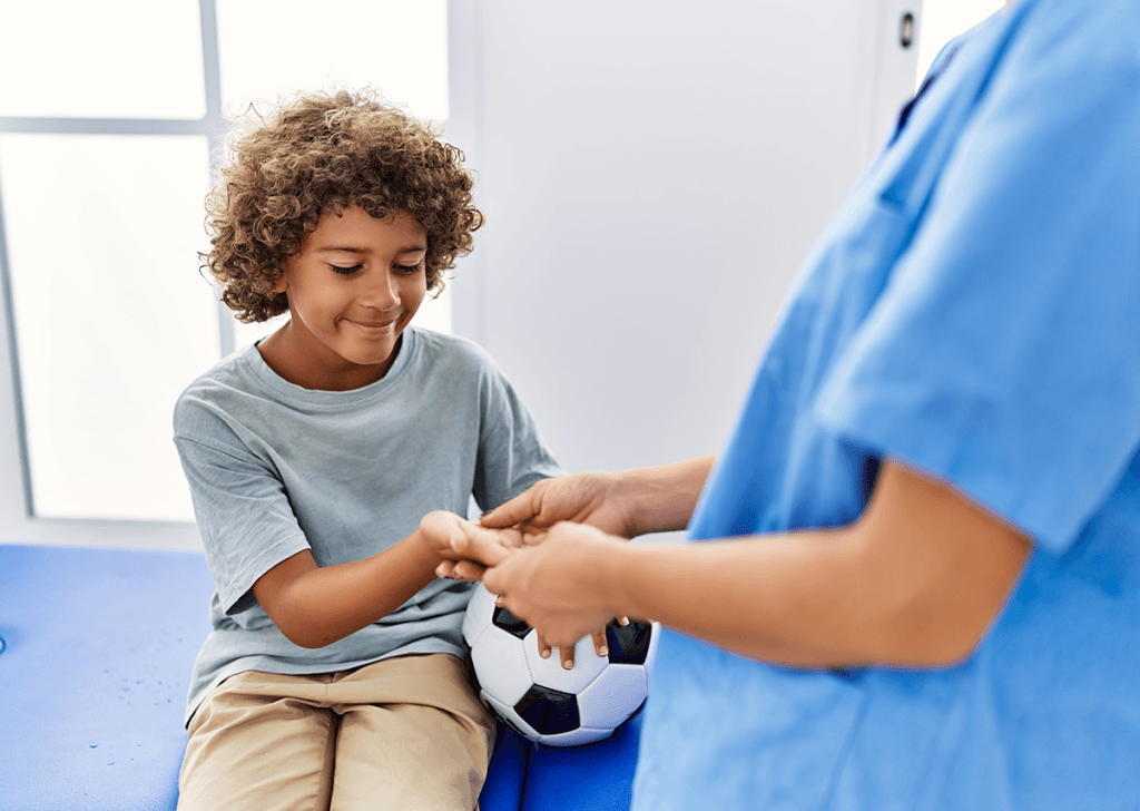 Boy holding a soccer ball getting a sports physical from a doctor